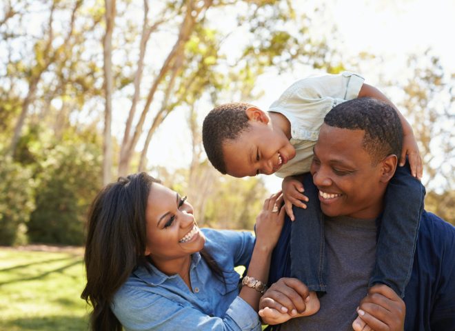 mother, father, and son laughing in the park