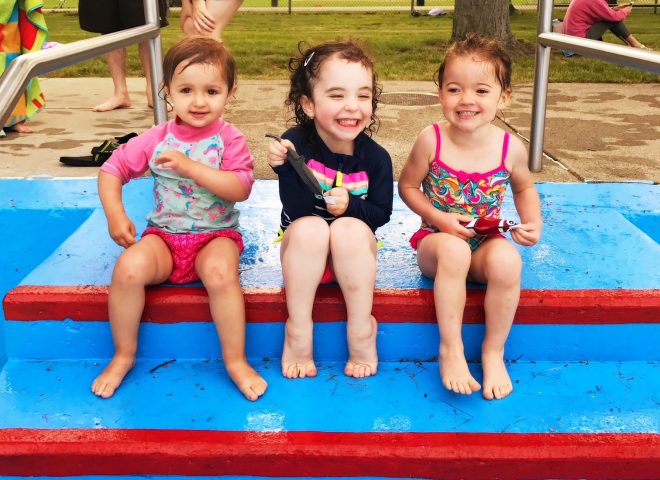 Three little kids on the steps of a pool